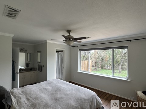 A bedroom with a large bed and a ceiling fan.
