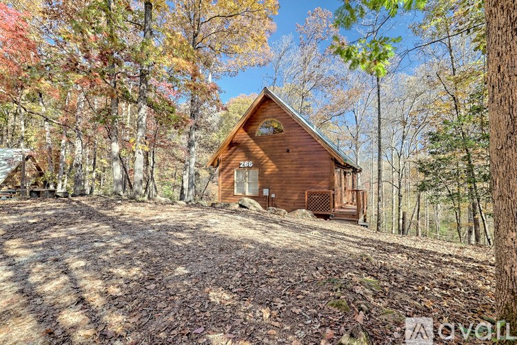 A wooden cabin is surrounded by trees with autumn leaves.
