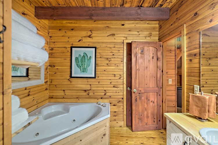 A wooden bathroom with a white tub and a wooden door.