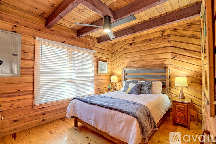 A bedroom with wooden walls and a bed with a white comforter.