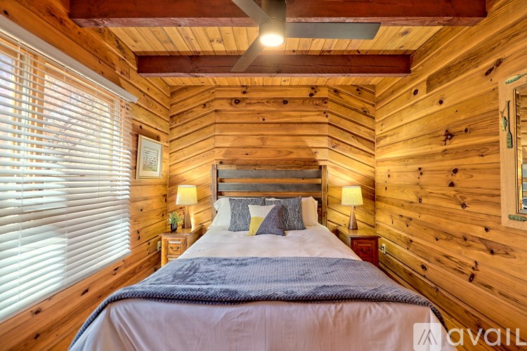 A bedroom with a bed, two lamps, and a window with blinds.