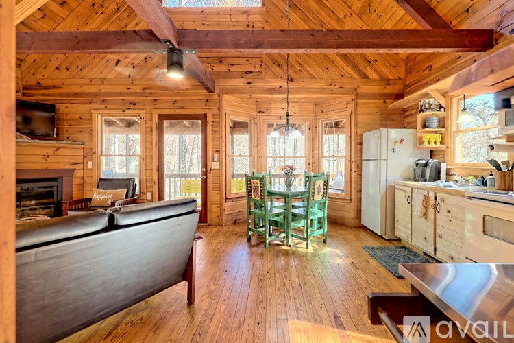 A wooden cabin with a couch, chairs, and a fireplace.