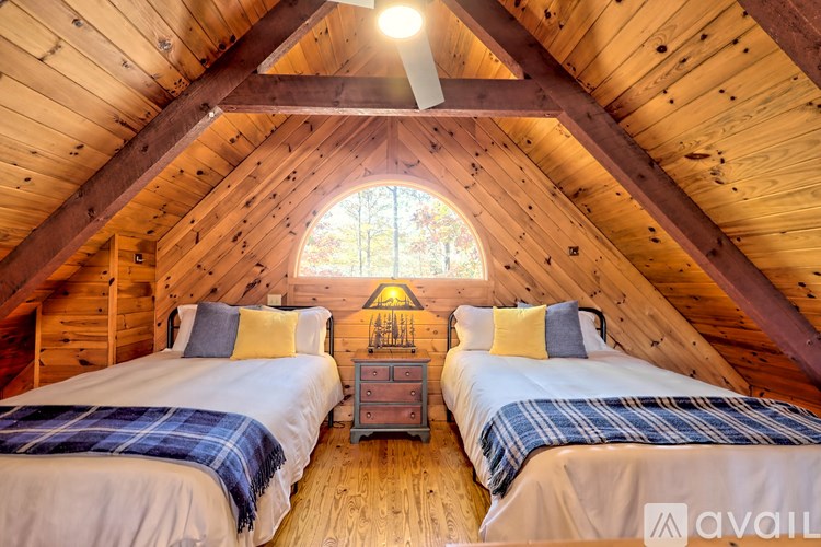 Two twin beds in a wooden cabin with a window above them.
