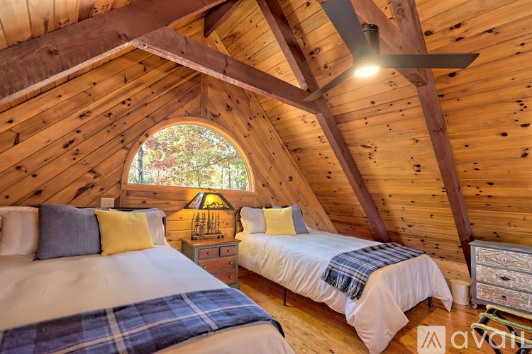 A bedroom with wooden walls and ceiling, two beds, and a ceiling fan.