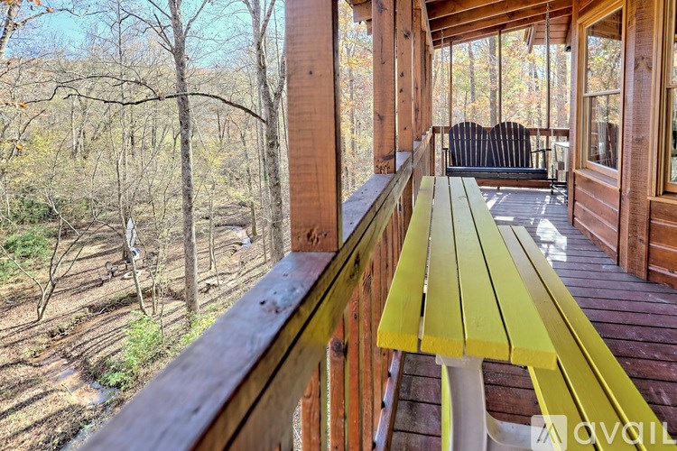 A wooden deck with a yellow bench overlooking a forest.