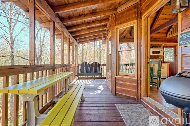 A wooden deck with a yellow bench and a grill.