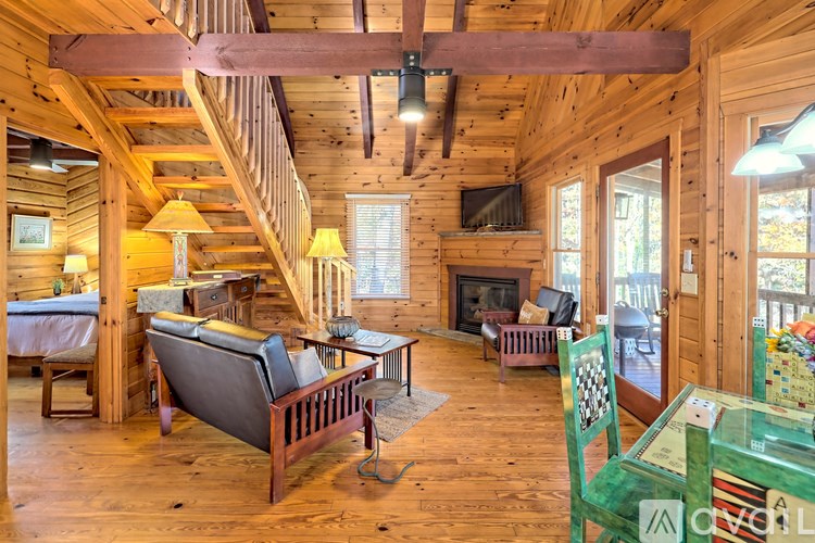 A cozy living room with a fireplace and a staircase.