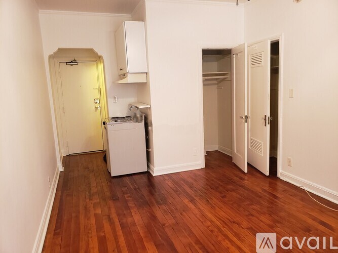 A room with wooden floors and white walls, with a washer and dryer in the corner.