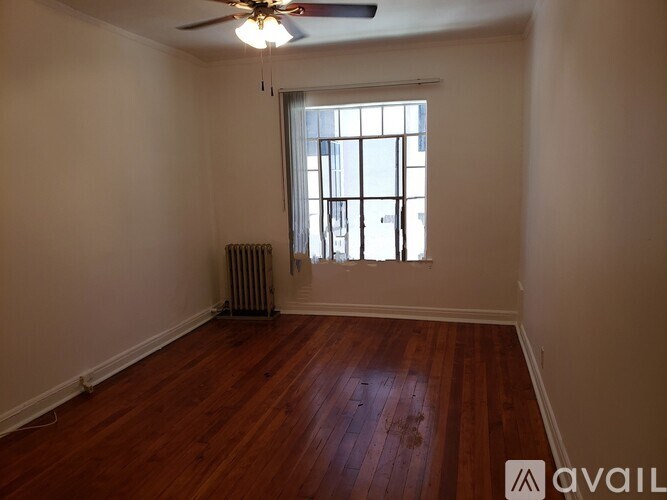 A room with wooden floors and a window with a view of a building outside.