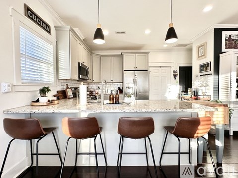 A kitchen with a bar area featuring a granite counter and bar stools.