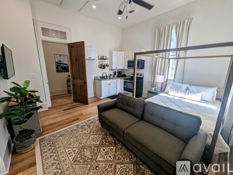 A living room with a grey sofa and a rug in the middle.