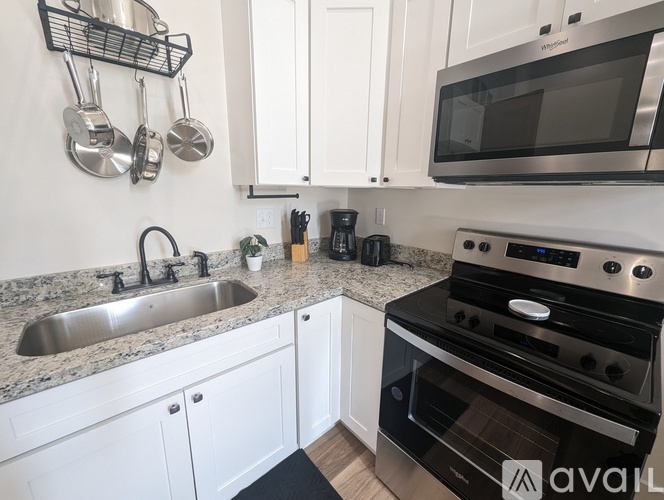 A kitchen with a sink, stove, and microwave.