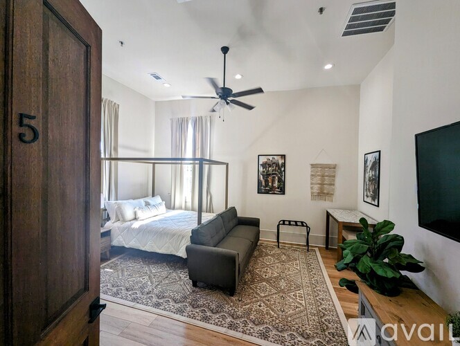 A bedroom with a bed, a couch, and a ceiling fan.