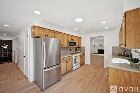 A kitchen with wooden cabinets and a stainless steel refrigerator.