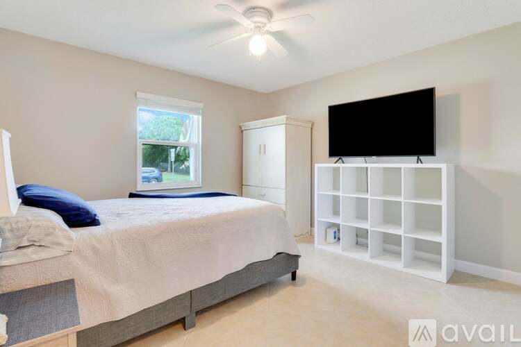 A bedroom with a bed, a television, and a window.