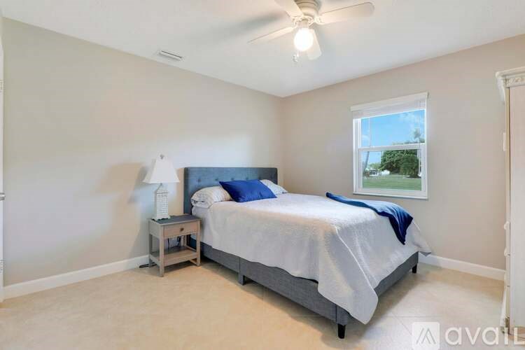 A bedroom with a bed, nightstand, and window.