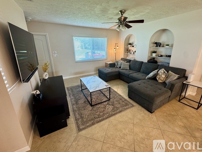 A living room with a grey couch and a black television.
