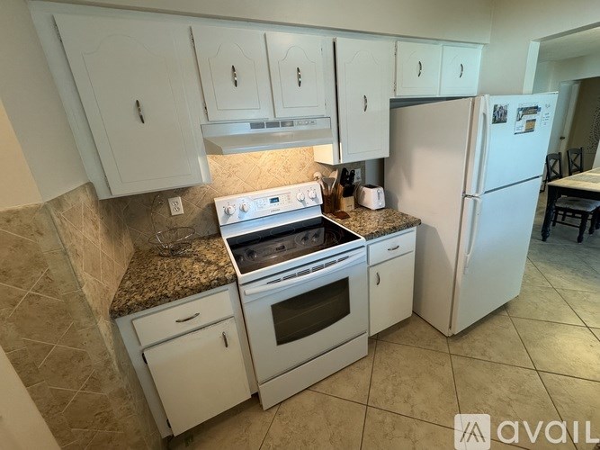 A kitchen with white appliances and cabinets.
