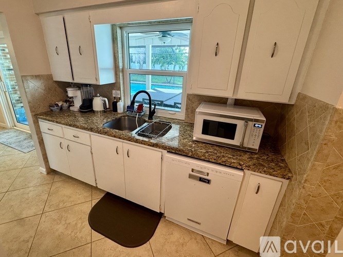 A kitchen with white cabinets and a granite countertop.