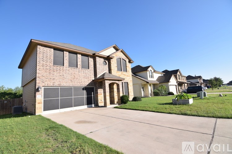 A large house with a garage is situated in a grassy area.