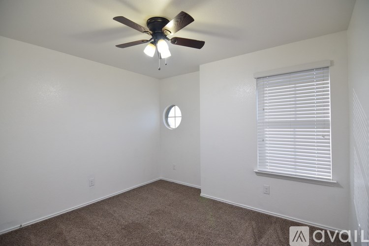A room with a ceiling fan and a window with blinds.