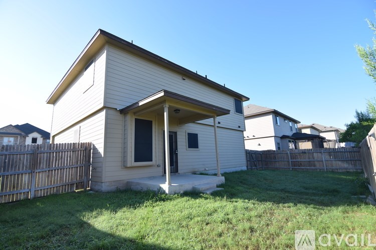 A small white house with a porch and a fence in front.