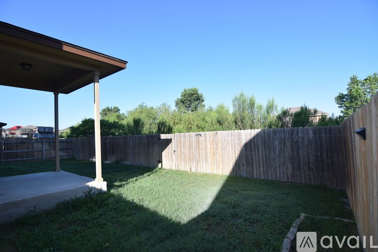 A backyard with a wooden fence and a covered patio area.