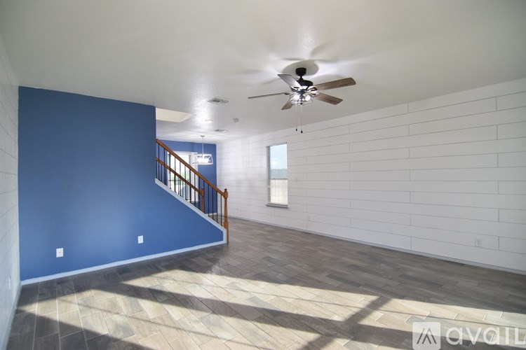 A room with a ceiling fan and a staircase.