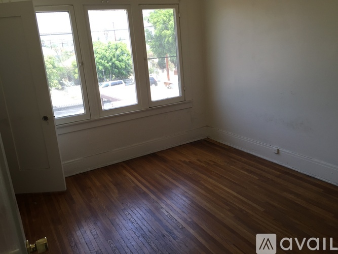 A room with wooden floors and a window overlooking a street.