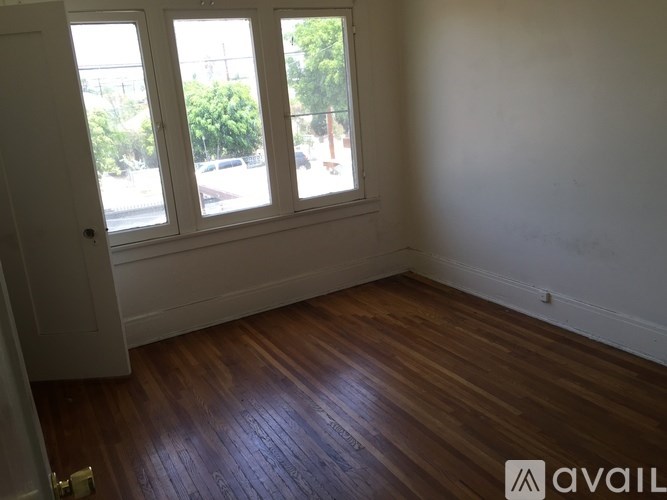 A room with wooden floors and a window overlooking a street.