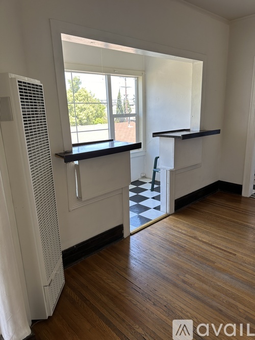 A room with wooden floors and a window with a view of trees.