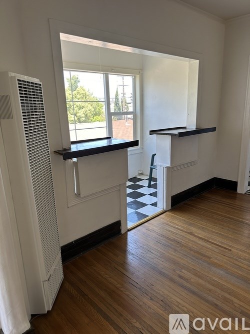 A room with wooden floors and a window with a view of trees.
