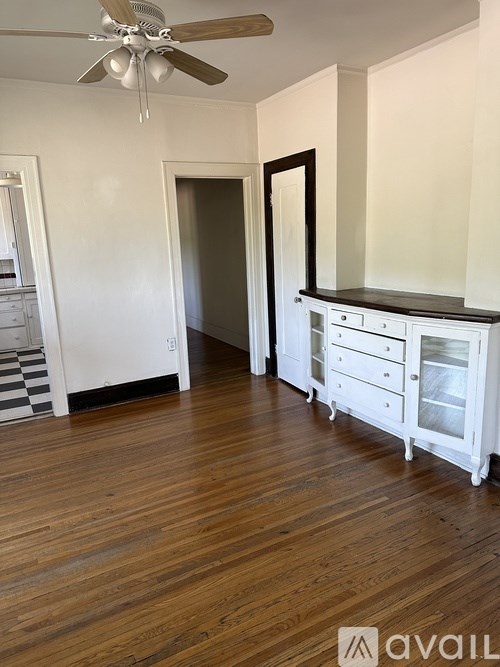 A room with a ceiling fan and wooden floors.
