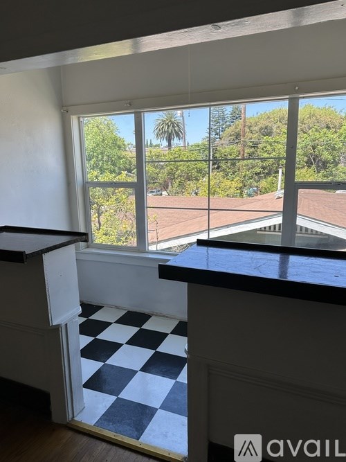 A kitchen with a checkered floor and a window overlooking a street.