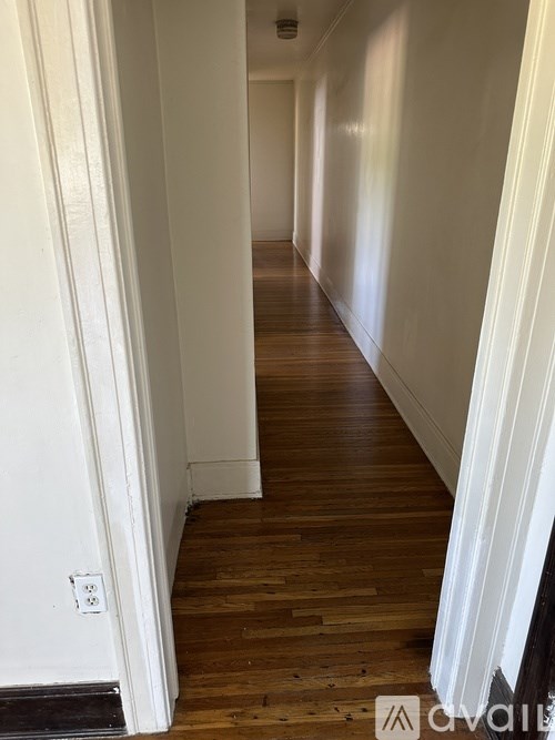 A long hallway with wooden floors and white walls.