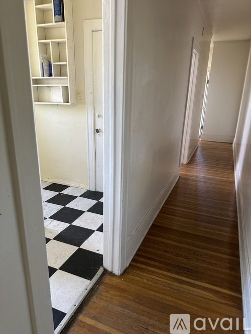 A hallway with a checkered floor and wooden flooring.
