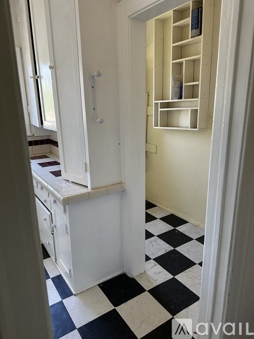 A white kitchen with black and white checkered floor.