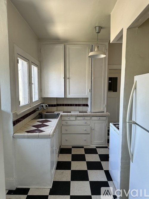 A kitchen with white cabinets and a black and white checkered floor.