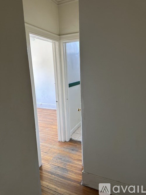 A hallway with a wooden floor and white walls.