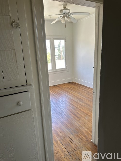 A room with a ceiling fan and wooden flooring.