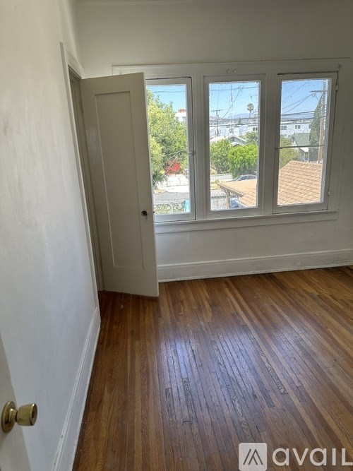 A room with a wooden floor and a door leading to a balcony.