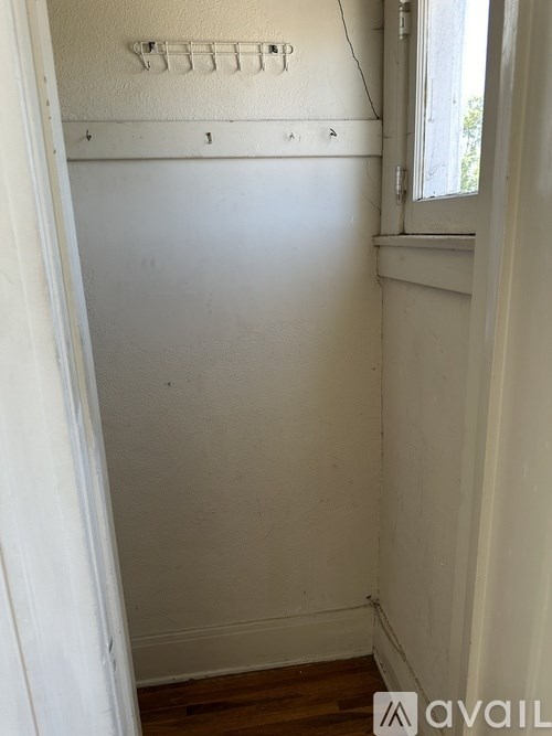 A small, empty room with a window and a white wall.