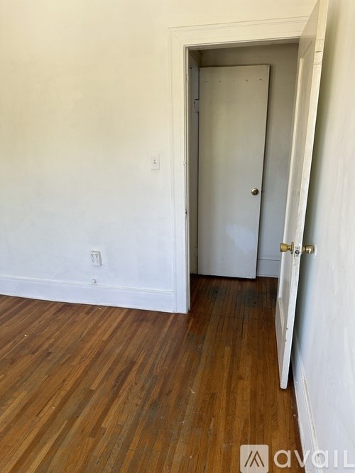 A room with a white door and wooden flooring.