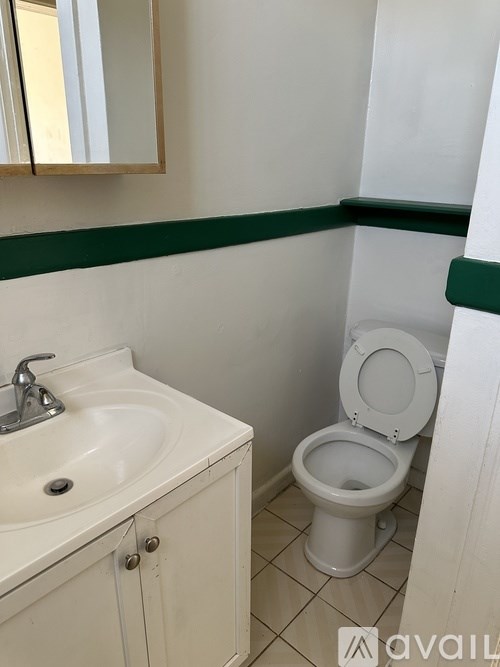 A white toilet sits next to a white sink in a bathroom.