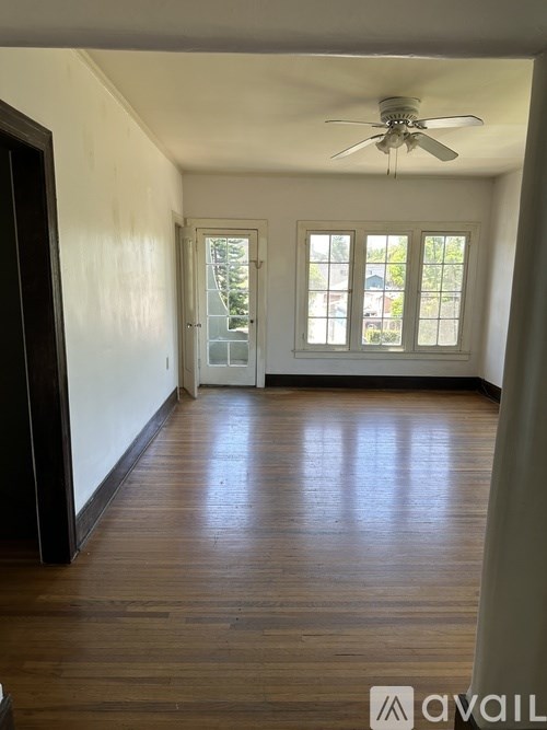 A room with a ceiling fan and wooden flooring.
