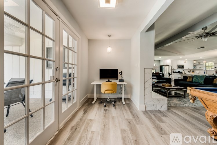 A room with a desk and a chair in front of a glass door.