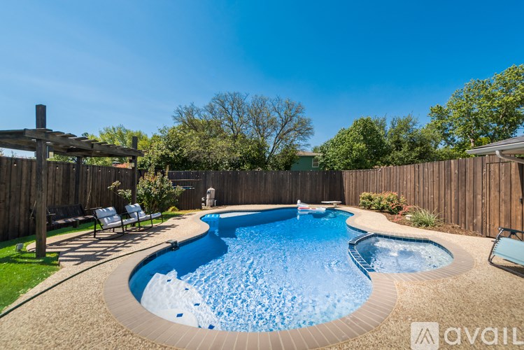 A backyard with a blue pool and a wooden fence.