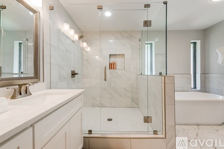 A modern bathroom with a marble shower and a white bathtub.