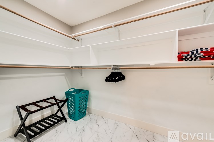 A white shelf with a black bag and a blue container on it.