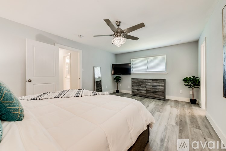 A bedroom with a bed, dresser, and ceiling fan.